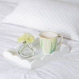 Addison Ross White Scalloped tray with coffee cup and vase with yellow flowers on a bed