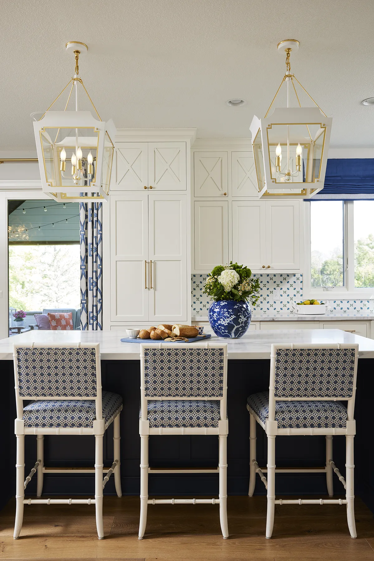 Bright white luxury kitchen with custom cabinetry, dual white open lantern pendant lights, and a matching kitchen island