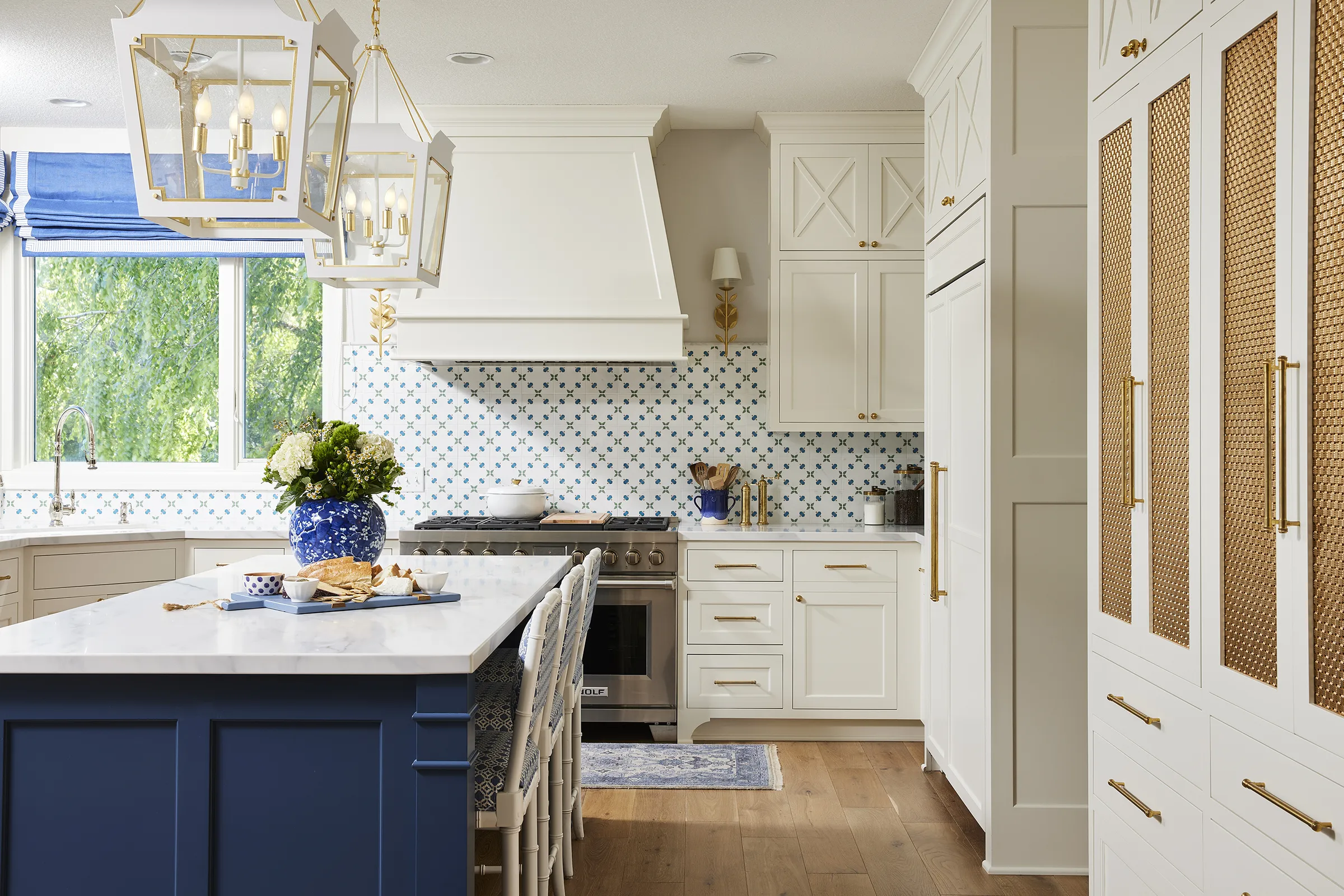 Bright white kitchen with blue island and brass accents